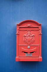 Perfect red letter box on a plain blue wall surface.