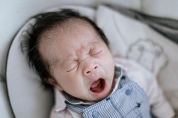 Yawning asian newborn baby, ready for nap