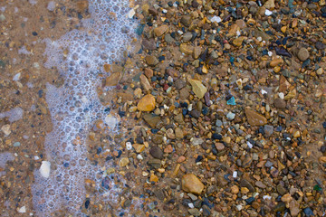 Stones under the sea wave on the shore. copy space, top view