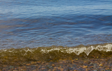 Rocky shore with a sea wave. Vacation at sea in the summer.