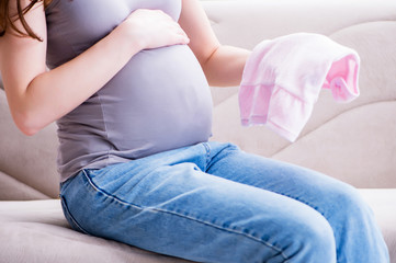 Fototapeta premium Pregnant woman with a belly tummy sitting on a sofa at home