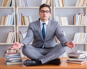 Businessman student in lotus position concentrating in the libr