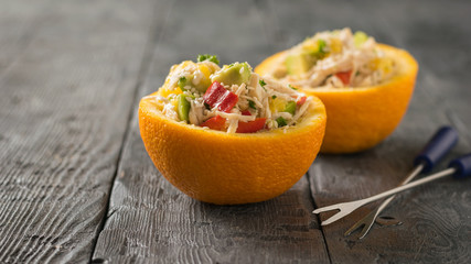 Two halves of an orange with a salad and two forks with blue handles.