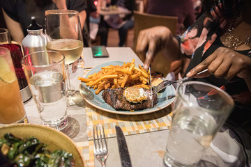 a close up of steak and fries dinner on a table at a restaurant in warm tone lighting