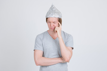 Stressed young man with tinfoil hat as conspiracy theory concept thinking
