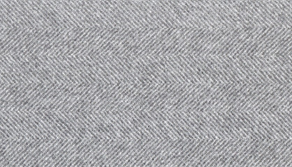 Light gray woolen fabric striped zigzag. Herringbone tweed, Wool Background Texture. Coat close-up. Expensive men's suit fabric. Virgin wool extra-fine. High resolution