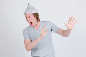 Stressed young man with tinfoil hat as conspiracy theory concept looking scared