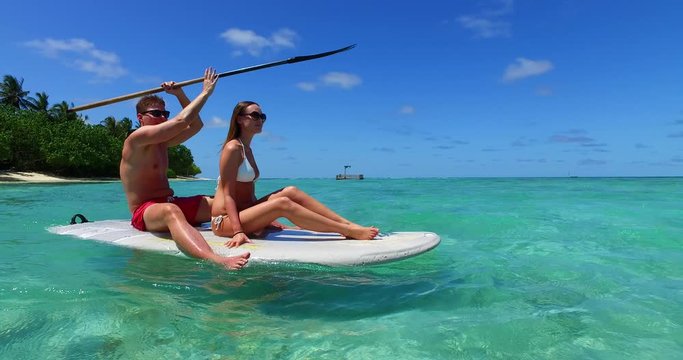 athletic couple relaxing during honeymoon holiday in the Caribbean with SUP paddling