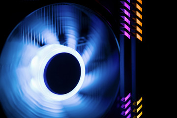 Inside a high performance computer. Rotating fan cooler with colorful  illumination blue.. RAM glows purple and yellow.