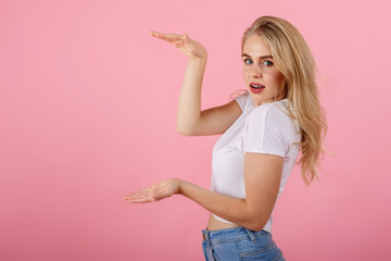 Young woman holding copyspace to insert an ad over pink background