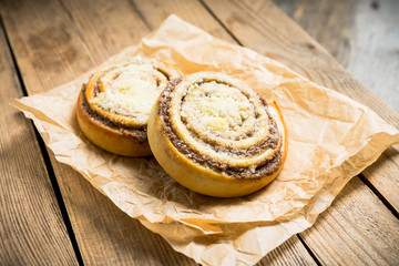 Fresh cinnamon buns on the rustic wooden background. Selective focus. Shallow depth of field.