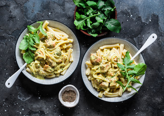 Curried creamy salmon with pasta on a dark background, top view