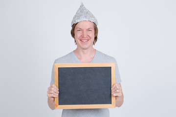 Happy young man with tin foil hat holding blackboard