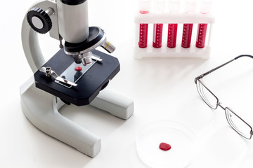 Blood testing laboratory. Samples viewing under microscope near tubes on white background top view copy space