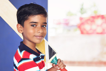 Portrait of indian boy posing to camera with cricket bat