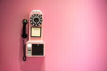 Old vintage phone hanging on a pink wall with copy space - 298202230