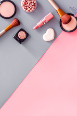 Makeup concept. Frame with decorative cosmetics and brushes on pink and grey background top view copy space