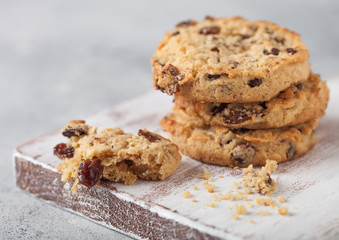 Homemade organic oatmeal cookies with raisins and apricots on white chopping board light background.