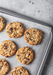 Homemade organic oatmeal cookies with raisins in baking tray on tracingpaper background. Top view