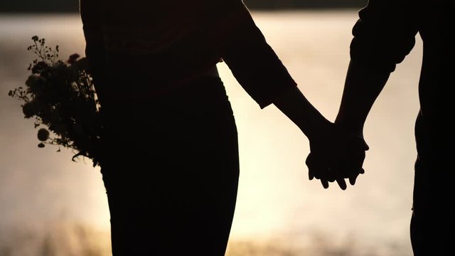silhouette lovers hold hands together love each other forever during the sunset golden light, romantic concept.