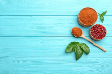 Flat lay composition of red powdered pepper and corns on blue wooden table, space for text