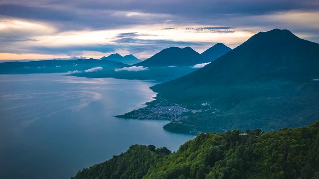 Aerial view of Lake atitlan in Guatemala during Sunrise, Errupting Volcano in Background, flying sideawards.