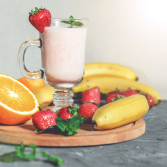 banana, strawberry and orange smoothies with mint on the table, front view