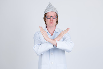 Serious young man doctor with tinfoil hat showing stop gesture