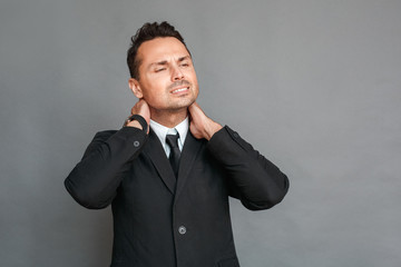 Businessman studio standing isolated on grey having neck muscle pain