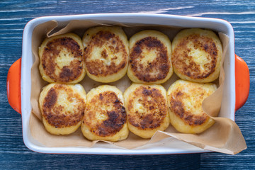 Cheesecakes in a baking dish. Cottage cheese pancakes or curd fritters in plate close view. Healthy and diet breakfast.