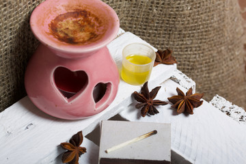 Aroma lamp stands on a wooden box. Near the oil in the cap and anise stars.