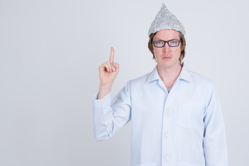 Young man doctor with tinfoil hat pointing up