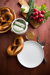 Münchener Weißwurst in Terrine mit bayrischer süßen Senf, Brezel, Radieschen, Schnittlauch und Butter auf Holz Tisch