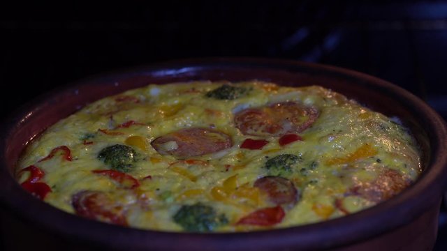 Ceramic bowl with vegetable frittata, simple vegetarian food. Frittata with egg, tomato, pepper, onion, broccoli and cheese , close up. Italian egg omelette in oven