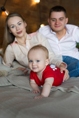 Parents and their child lying on bed. Mom, dad and baby. Portrait of young family. Happy family life. Man was born.