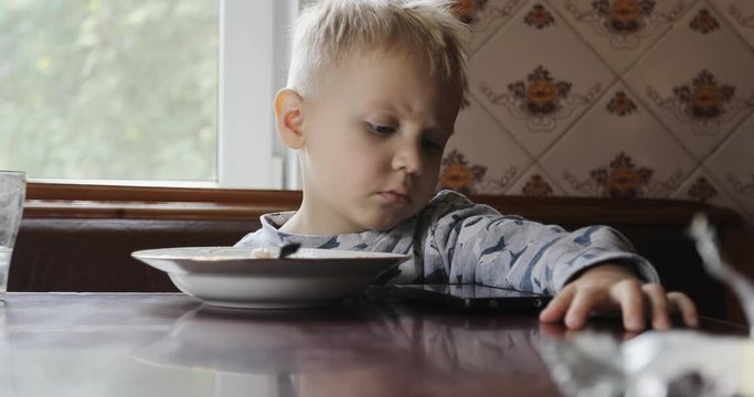 Portrait of little boy eatting porridge.