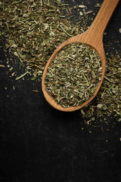 herbs of Provence seasoning for food in wooden spoon and black background isolated. macro shot