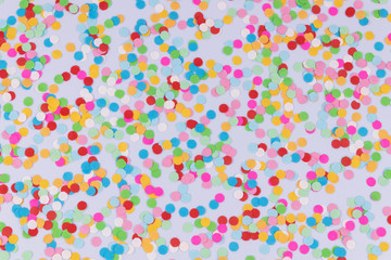 A pattern of colorful bright round multicolored confetti scattered on white background