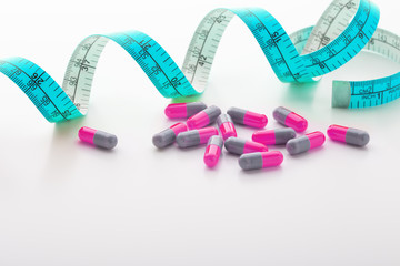 Diet supplements, pills, pink capsule with blue measuring tape