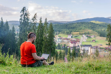 Remote work concept: a man working on a laptop outdoors. Work during the holidays, workaholic. Freelance