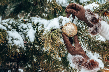 Girl holds a Christmas toy. Hands in leather gloves closeup. Seasonal holidays and celebrations. Traditional New Year and Christmas decor.