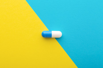 Pharmaceutical pill on yellow blue background