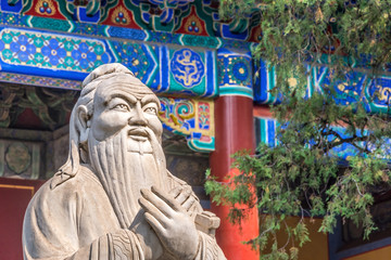 Closeup of Confucius statue in front of colorful ancient temple with beautiful ornaments - obrazy, fototapety, plakaty