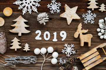 White Letters Building The Word 2019. Wooden Christmas Decoration Like Tree, Sled And Star. Brown Wooden Background