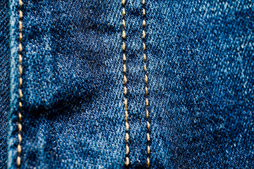 Close-up texture of blue denim stitched with orange thread