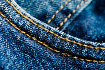 Close-up texture of blue denim stitched with orange thread