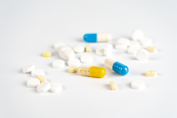 Many little white tablets and colorful tablet capsules on white background