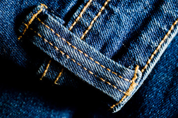 Close-up texture of blue denim stitched with orange thread
