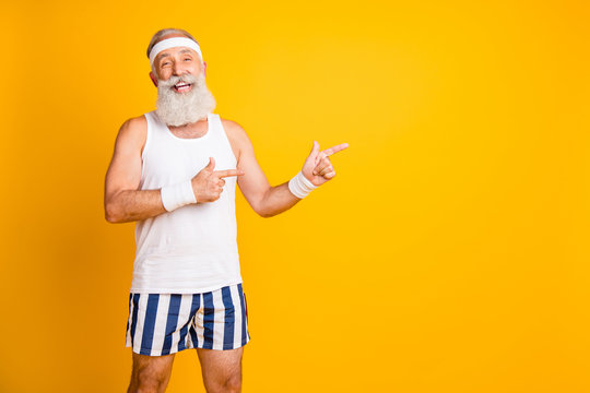 Photo of aged model white hair guy directing fingers empty space advising choose healthy sports supplements wear tank-top shorts sweatband isolated yellow color background