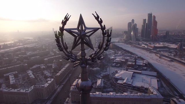 Star spire snow roofs of old soviet stalin high-rice building skyscraper. Winter Russia Moscow city center. Bright sun. From a great height overall plan. Close drone aerial flight